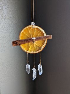 an orange slice hanging from a string with some ice cubes on it and a cinnamon stick sticking out of it