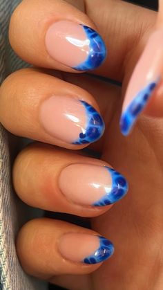 a woman's hand with blue and pink nail polish on her nails, while she has