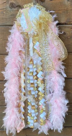 the pink and gold feather boa is hanging on a wooden wall