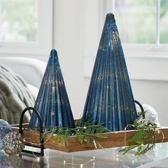 two blue vases on a coffee table with christmas decorations in front of the window