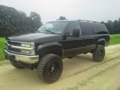 a black truck parked on top of a dirt road