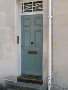 a blue door on the side of a building with steps leading up to it's entrance