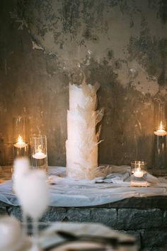 a table topped with candles next to a cake covered in frosted icing and sitting on top of a stone slab