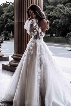 a woman in a white wedding dress standing on the sidewalk with her hands to her face