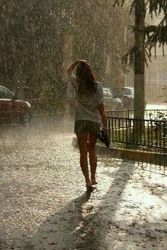 a woman walking in the rain with an umbrella over her head while it is raining