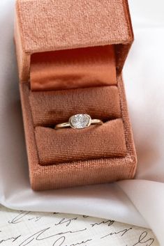 an open ring box with a diamond in it