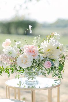 a vase filled with white and pink flowers on top of a table next to a mirror