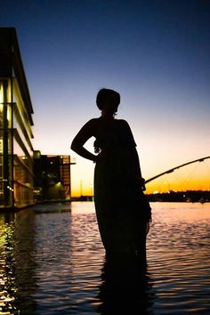 a woman is standing in the water with her hands on her hips as she fishes