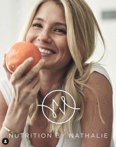 a woman holding an orange and smiling for the camera