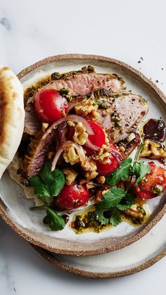 a white plate topped with meat and veggies on top of a marble counter