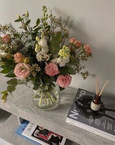 a vase filled with flowers sitting on top of a table next to books and candles