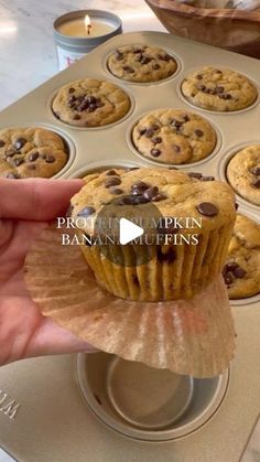 a person holding a muffin in front of a cupcake