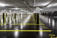 an empty parking garage with yellow lines painted on the floor and white walls, along with dark floors