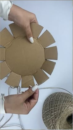 someone is making a paper sunburst out of cardboard and twine with yarn