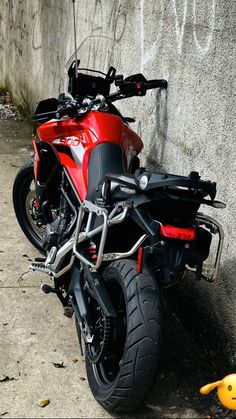 a red motorcycle parked next to a cement wall