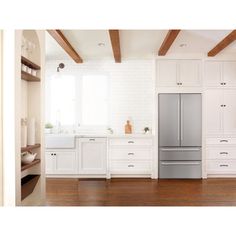 a kitchen with white cabinets and wood floors