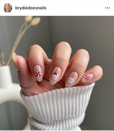 a woman's hand with white and red nail designs on it