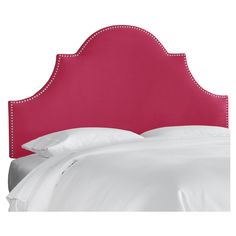 a pink headboard with studded trim and white sheets