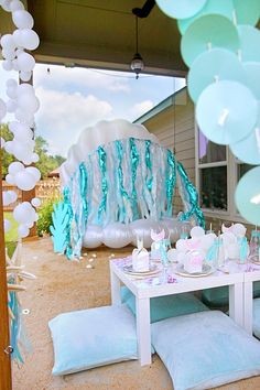 a table with blue and white decorations in front of a party set up for a baby's first birthday