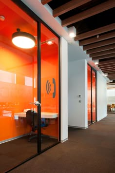 an office with orange glass walls and chairs