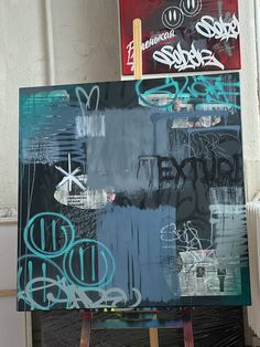 an easel with some graffiti on it in front of a wall