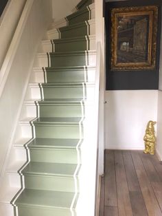 the stairs are painted green and white with gold accents on each handrail, along with an ornate framed painting