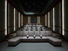 an empty theater room with couches and lights on the walls, along with two recliners