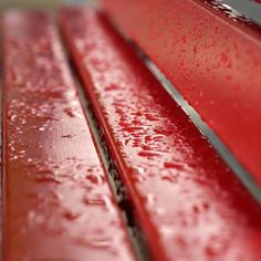 a red bench with water droplets on it