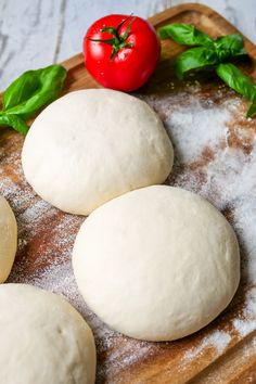 three round doughnuts sitting on top of a wooden cutting board next to a tomato