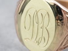 "Featuring components from different eras, this one-of-a-kind signet ring is a delightful combination of green and rose gold! The monogram at the center is beautifully engraved in ornate French script, while the ring's shoulders have subtle motifs that catch the light and shine. Please note that this signet ring has an original monogram, and unfortunately, this piece cannot be altered without affecting the quality of the piece. Please feel free to contact us to help you find your perfect signet 14k Gold Engraved Ring With Initials For Collectors, Luxury Engraved Signet Ring Collectible, Collectible Yellow Gold Signet Ring With Initials, Collectible Yellow Gold Engraved Ring With Hallmarks, Collectible Engraved Yellow Gold Ring With Hallmarks, Oval Engraved Signet Ring For Collectors, Luxury Oval Signet Ring With Hallmarks, Collectible Yellow Gold Signet Ring With Engraving Option, Luxury Yellow Gold Signet Ring With Maker's Mark