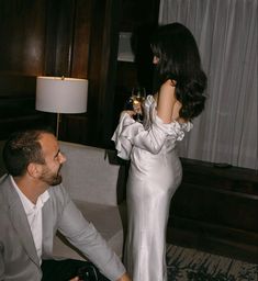 a man and woman sitting on the floor next to each other in front of a lamp