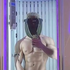 a man with no shirt is taking a selfie in front of a mirror wearing a mask