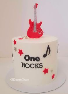 a white cake with red stars and a guitar on top that says, one rocks