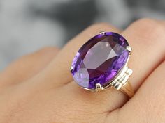 This is a stunning stone, with a rich color and a sophisticated cut. This natural, well-cut amethyst at the center glimmers with its medium-deep eggplant purple color that flashes with pops of violet and raspberry. We've set this pretty gem into a vintage mounting of yellow gold. Easy to wear, this sits comfortably on the finger and is a nice, bold size that is sure to make a statement! Metal: 14K Yellow Gold Gem: Amethyst 19.50 Carats Gem Measurements: 15.9 x 20.8 mm, Oval Ring Size: 5.50 Marks Amethyst Stone Ring, Oval Stone Ring, Amethyst Cocktail Ring, Gold Drop Necklace, Big Stone Ring, Right Hand Ring, Repurposed Jewelry, Golden Ring, Special Ring