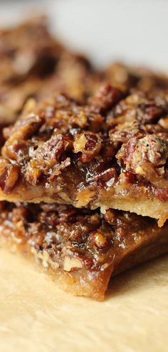 two pieces of pecan bar sitting on top of a wooden cutting board