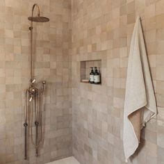 a bathroom with a shower head, towel and soap dispenser on the wall