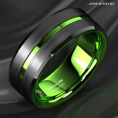 a green and black wedding ring on a grey background with the words,'shop now for