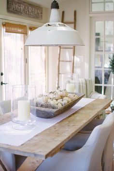 a wooden table topped with a bowl of muffins next to a light fixture