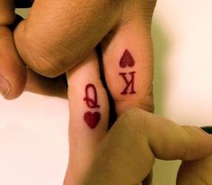 two people with matching tattoos on their fingers holding each other's hands and the word love is written in red ink