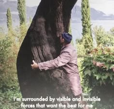 a man climbing up the side of a tree with a quote on it that reads, i'm surrounded by visible and invisible forces that want the best for me