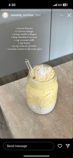 a jar filled with yellow liquid sitting on top of a counter next to a phone