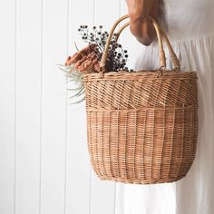 a woman holding a wicker basket with dried flowers in it