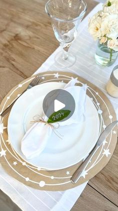 the table is set with white flowers and silverware