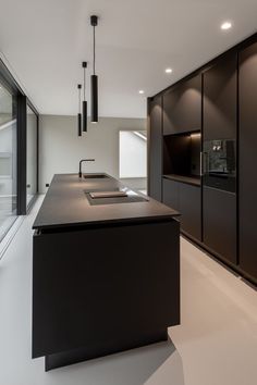 a kitchen with an island counter top and black cabinets in front of a large window