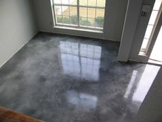 an empty room with concrete floors and windows