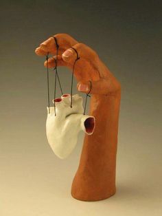 a clay hand holding an object with strings attached to it's thumb and fingers