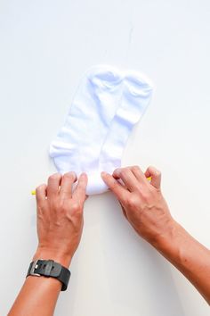 two hands are working on a pair of white socks with one hand reaching for the sock