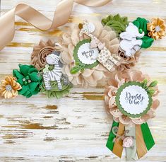 some flowers and ribbons on a white wooden surface with a ribbon around them that says daddy to be