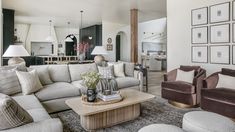 a living room with couches, chairs and pictures hanging on the wall above them