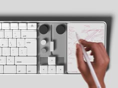 a hand is holding a white pen and writing on a computer keyboard, next to a drawing pad